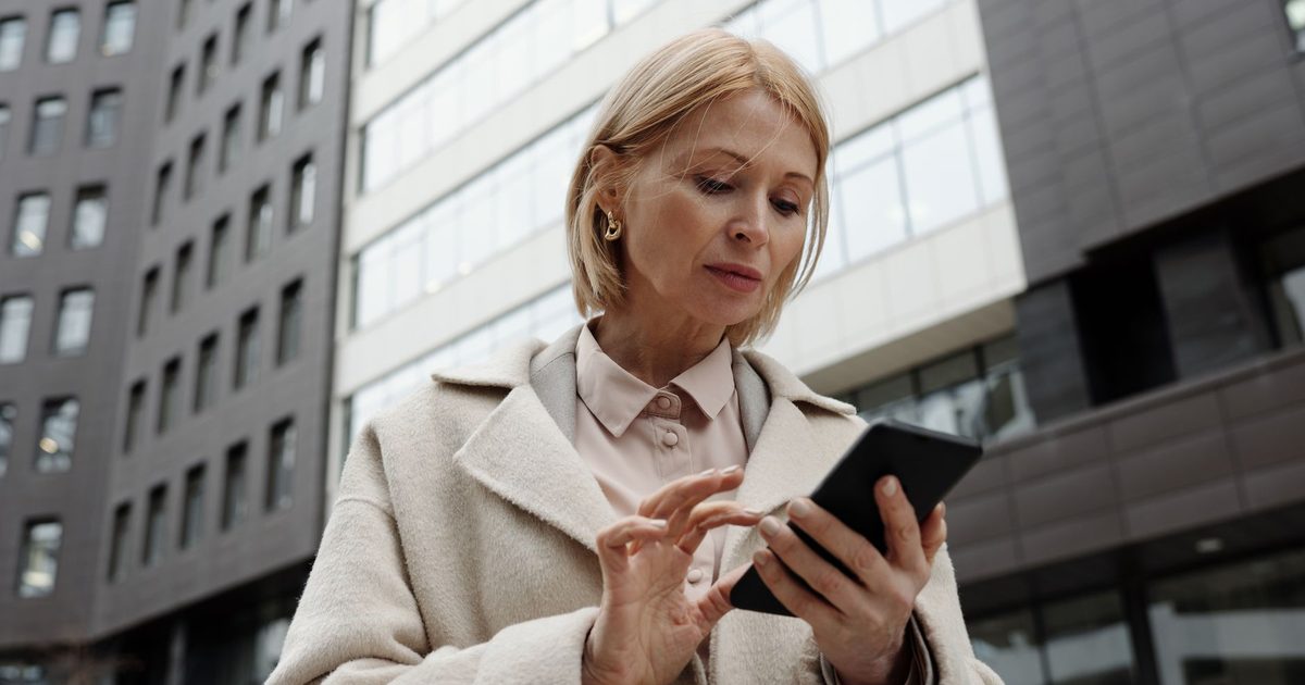 Femme en manteau consultant son téléphone dans une rue de la ville