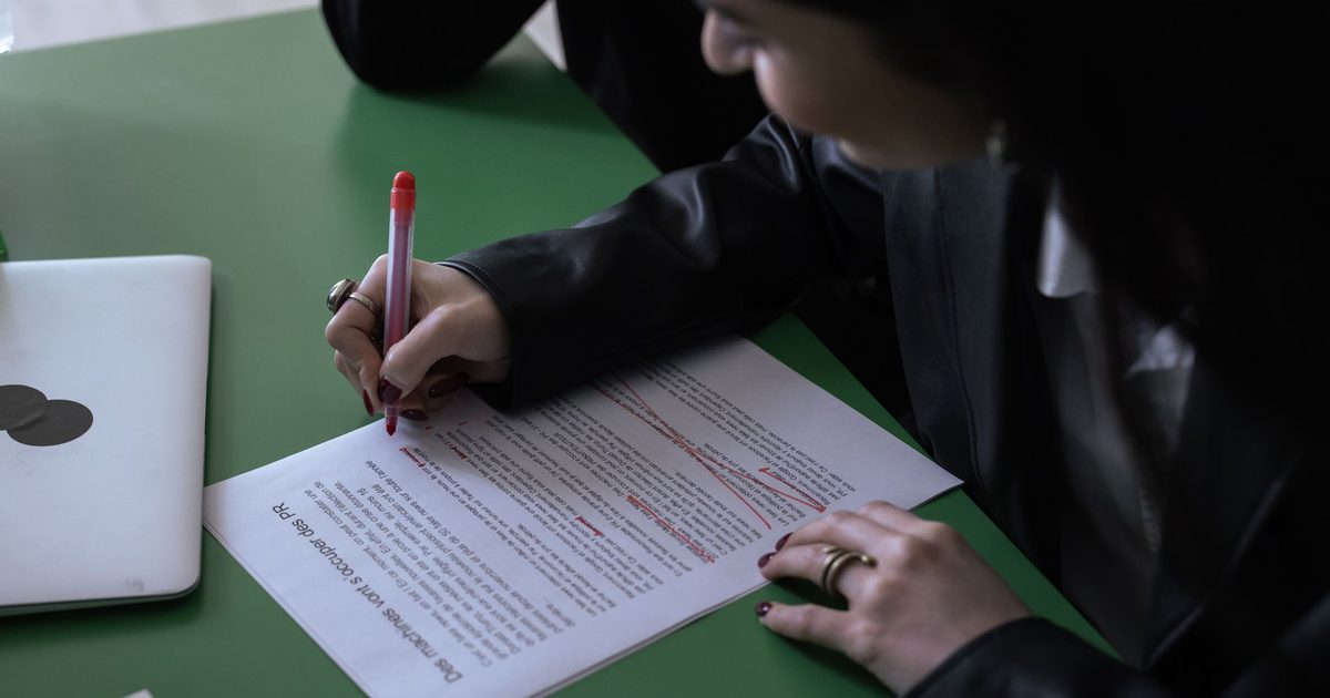 Personne annotant un document imprimé au stylo rouge